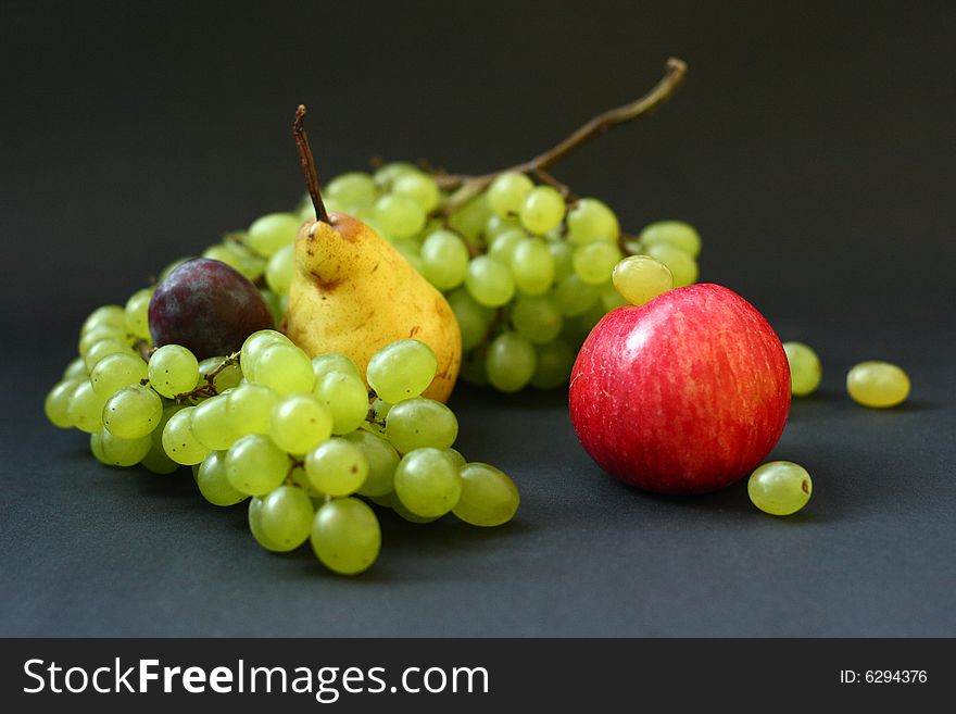 Red apple, pear, plum and grape on black background. Red apple, pear, plum and grape on black background