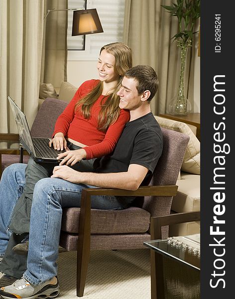 Young smiling, couple at home working on a laptop computer. Vertically framed photo. Young smiling, couple at home working on a laptop computer. Vertically framed photo.