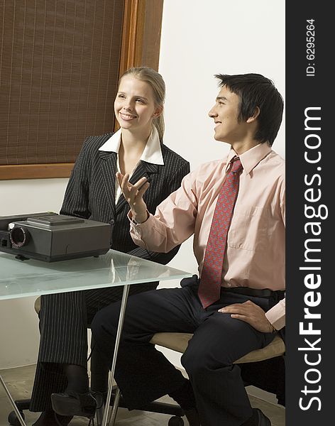 Business woman and man talking in a meeting in an office. Vertically framed photo.