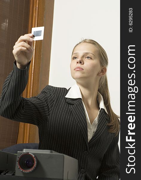 Woman looking serious as she looks at a slide next to a projector. Vertically framed photo. Woman looking serious as she looks at a slide next to a projector. Vertically framed photo.