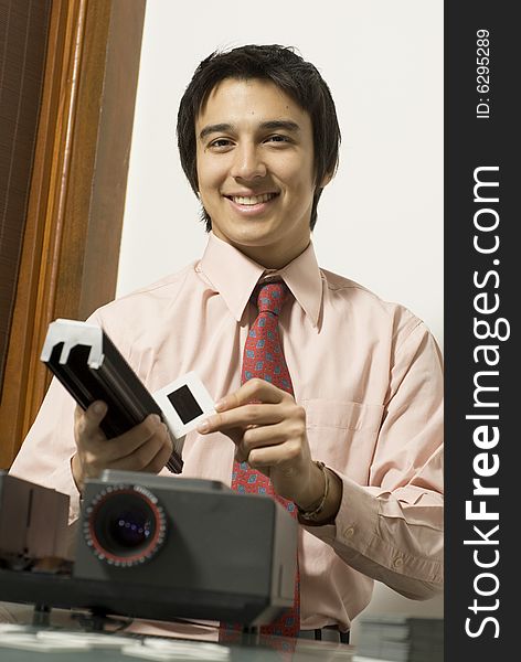Man smiling as he looks at a slide next to a projector. Vertically framed photo. Man smiling as he looks at a slide next to a projector. Vertically framed photo.