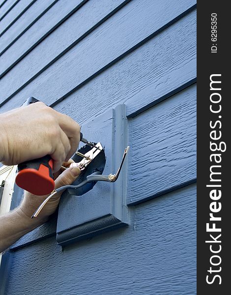 Hands fixing the wiring for a light fixture on a house. Vertically framed photo. Hands fixing the wiring for a light fixture on a house. Vertically framed photo.