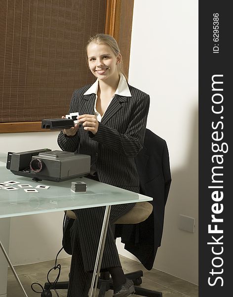 Woman smiling as she works a slide show projector. Vertically framed photo. Woman smiling as she works a slide show projector. Vertically framed photo.