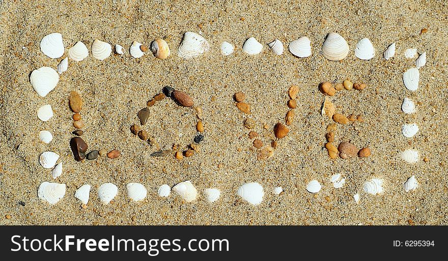 Love written in sand with rocks and shells. Love written in sand with rocks and shells