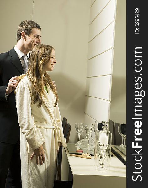 Smiling young couple standing in front of a mirror. Vertically framed photo. Smiling young couple standing in front of a mirror. Vertically framed photo.