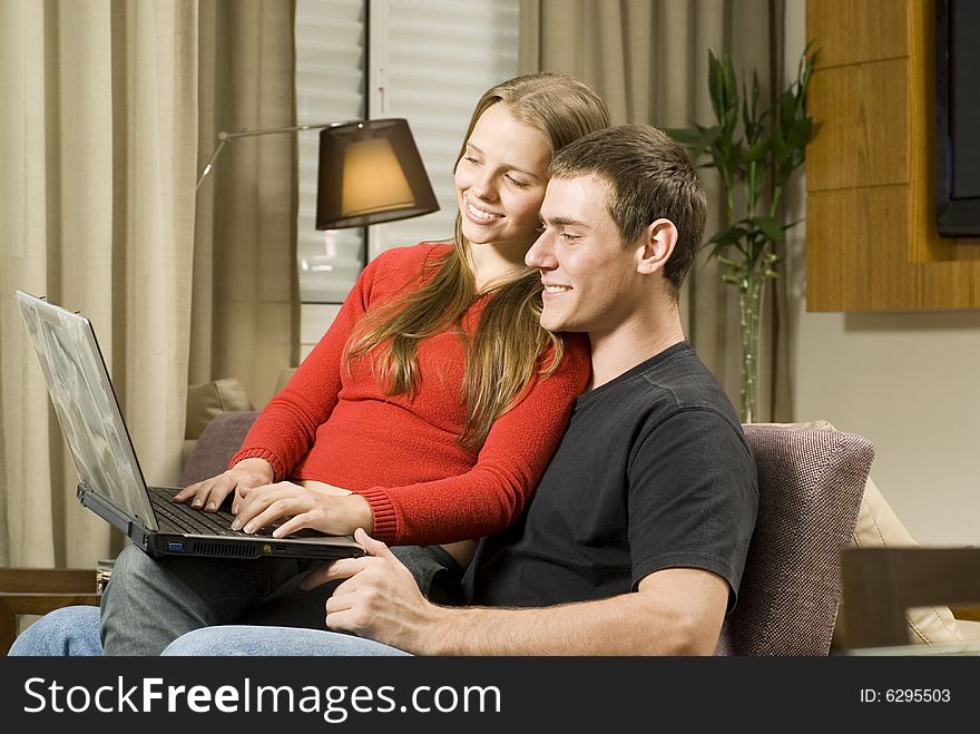 Young smiling, couple at home working on a laptop computer. Horizontally framed photo. Young smiling, couple at home working on a laptop computer. Horizontally framed photo.