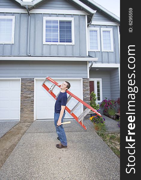 Laughing man standing in front of house holding ladder and hammer. Vertically framed photo. Laughing man standing in front of house holding ladder and hammer. Vertically framed photo.