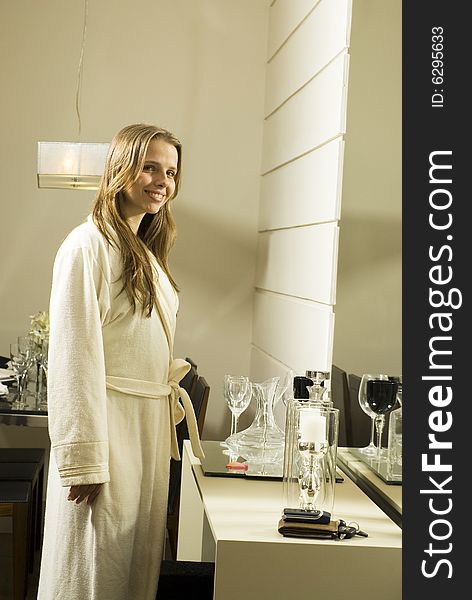 Woman smiling wearing a robe standing in a bathroom in front of a mirror. Vertically framed photo. Woman smiling wearing a robe standing in a bathroom in front of a mirror. Vertically framed photo.