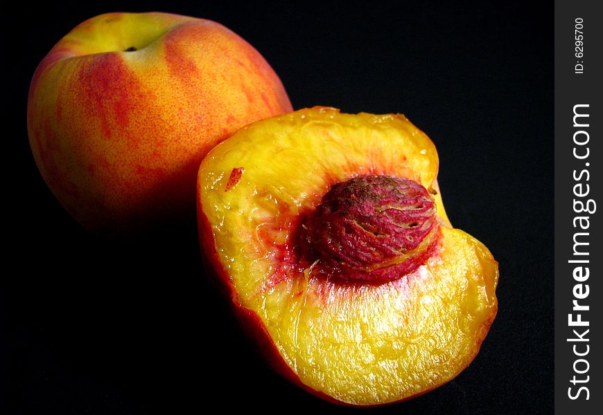 Two ripe peaches on a black background