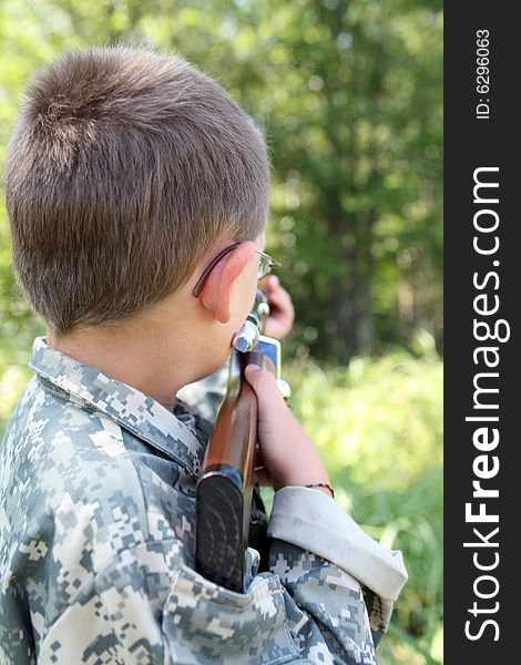 Young boy playing soldier outside with a toy rifle