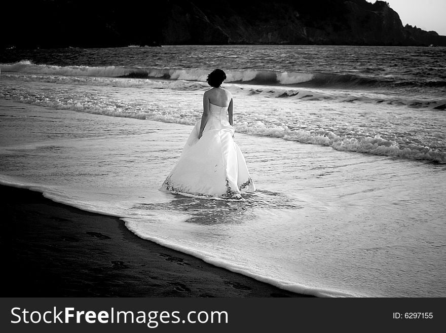 Bride wading in ocean water in San Francisco bay