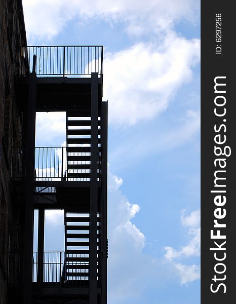 Silhouette of fire escape against cloudy blue sky