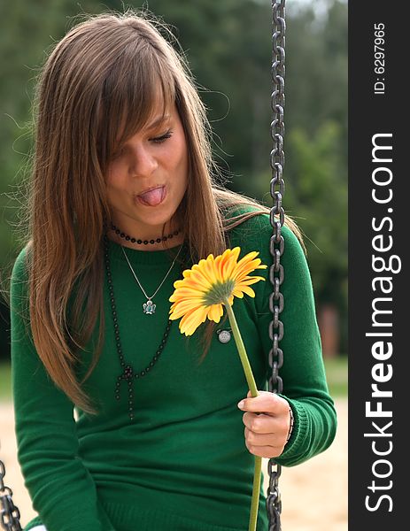 Photo presents a teenager on a swing looking on a flower. Photo presents a teenager on a swing looking on a flower