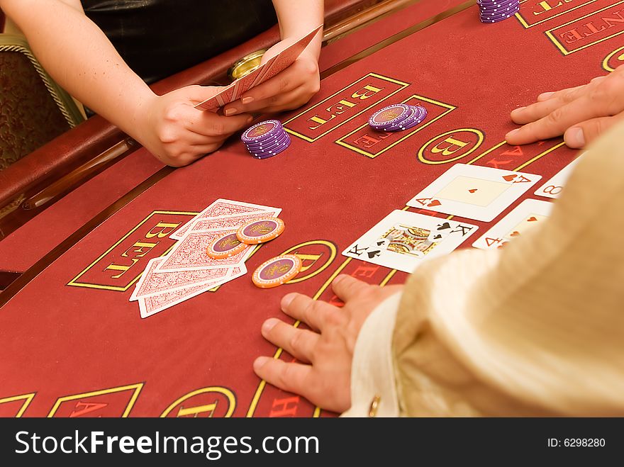 Cards in hands are on red table in casino. Cards in hands are on red table in casino