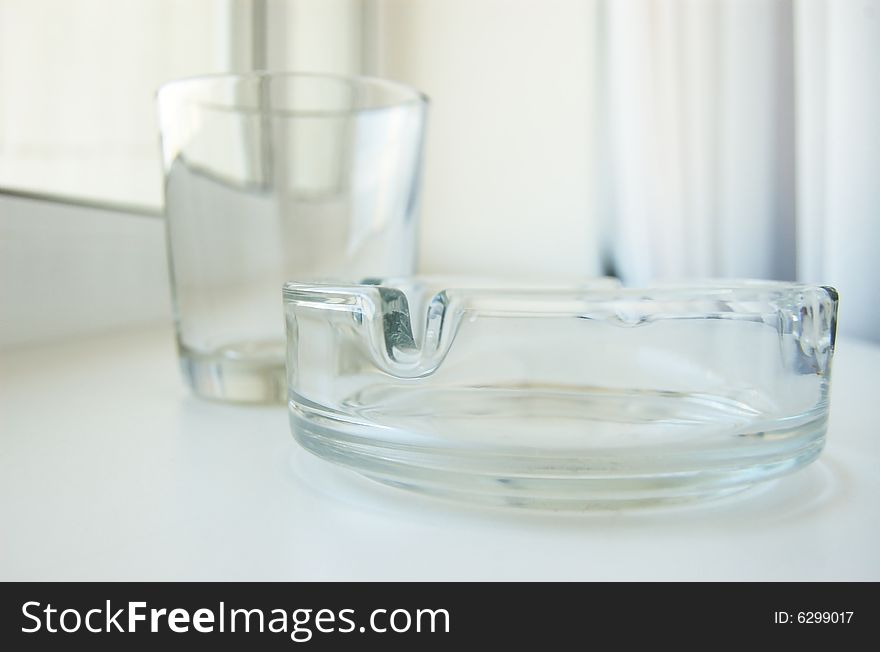 Transparent glass objects. Empty ashtray and glass.