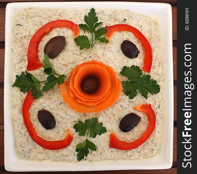 Appetizer salad in a white square bowl, with nice vegetable decoration