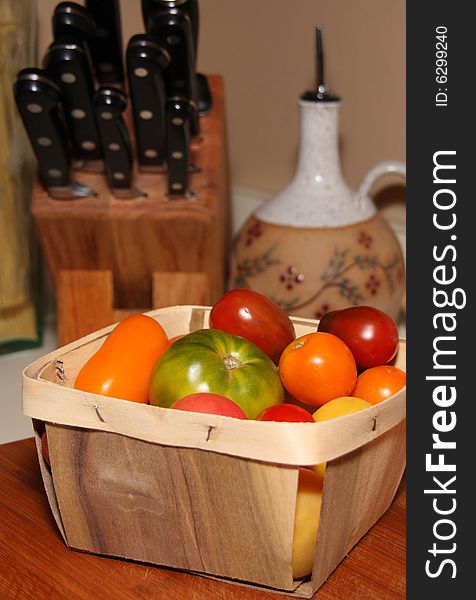 Green orange red and yellow tomatoes in a wooden basket. Green orange red and yellow tomatoes in a wooden basket