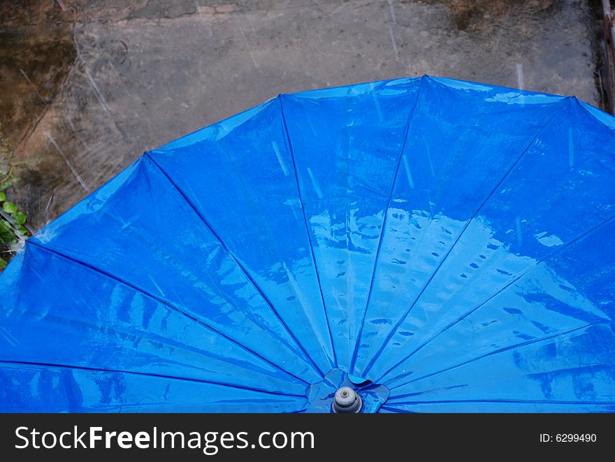 Blue umbrella on a terrace during a quick rain storm. Blue umbrella on a terrace during a quick rain storm