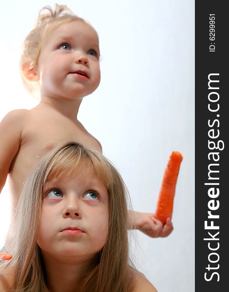 An image of two sisters eating orange carrot