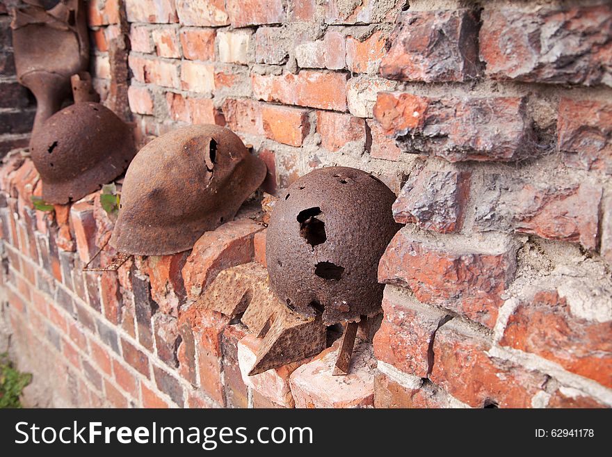 Three old rusty military helmets near the brick wall