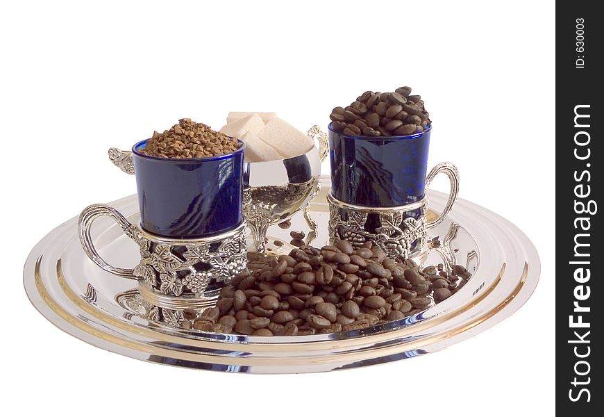 Two cups, refined sugar, instant coffee and coffee beans. Two cups, refined sugar, instant coffee and coffee beans