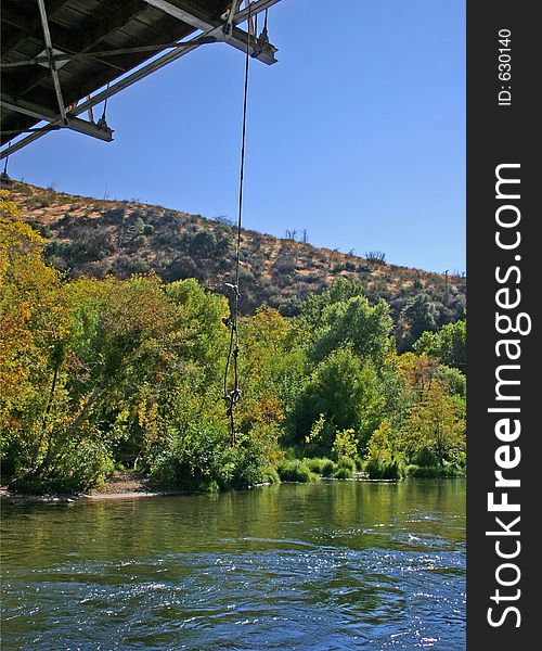 A swing rope hangs from a bridge promising swimming fun in the local swimming hole on the Kern River, Ca. A swing rope hangs from a bridge promising swimming fun in the local swimming hole on the Kern River, Ca.