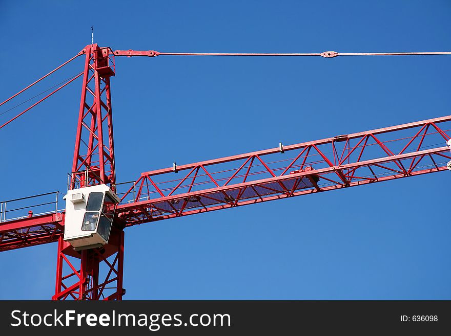 Red construction crane on clear blue sky background