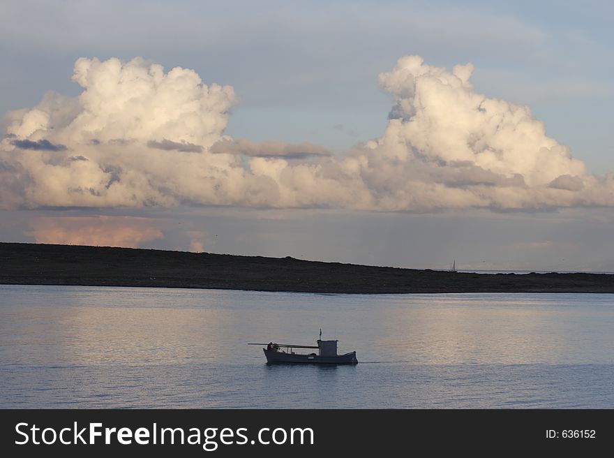 Fishing boat and big cloud in Stintino, Sardinia, Italy