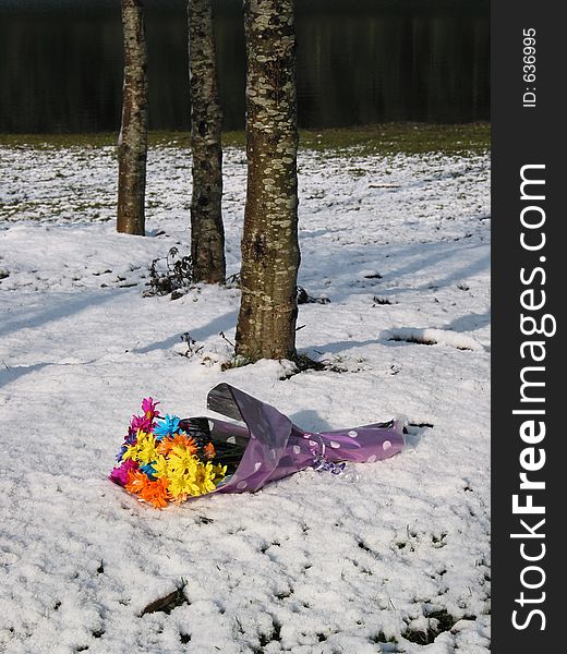 A discarded bouquet lays beneath the trees in the snow.