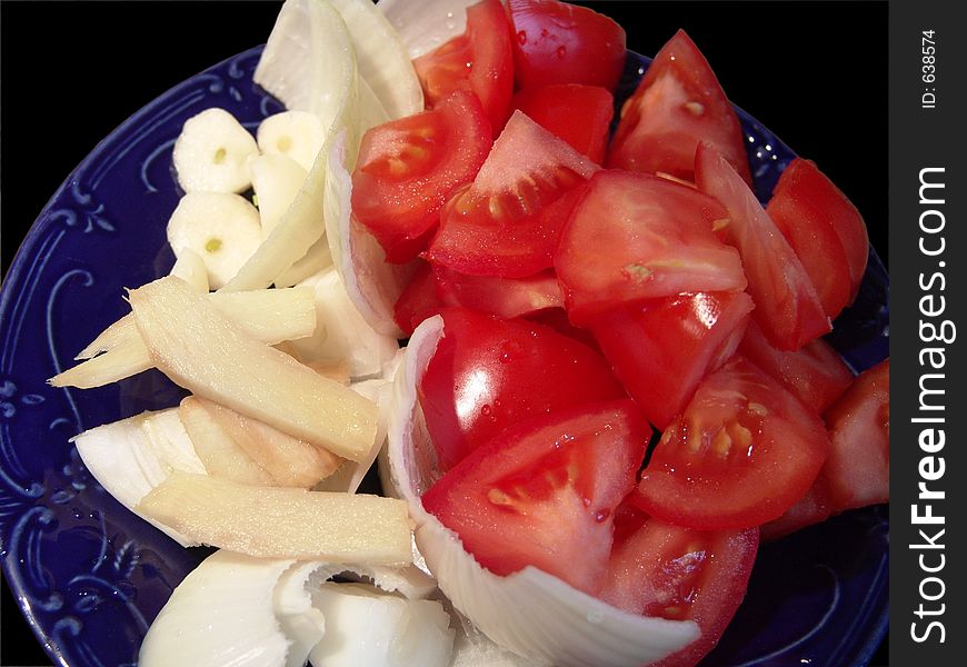 High resolution digital photo of tomatoes, onion, garlic and ginger on a porcelain plate. High resolution digital photo of tomatoes, onion, garlic and ginger on a porcelain plate