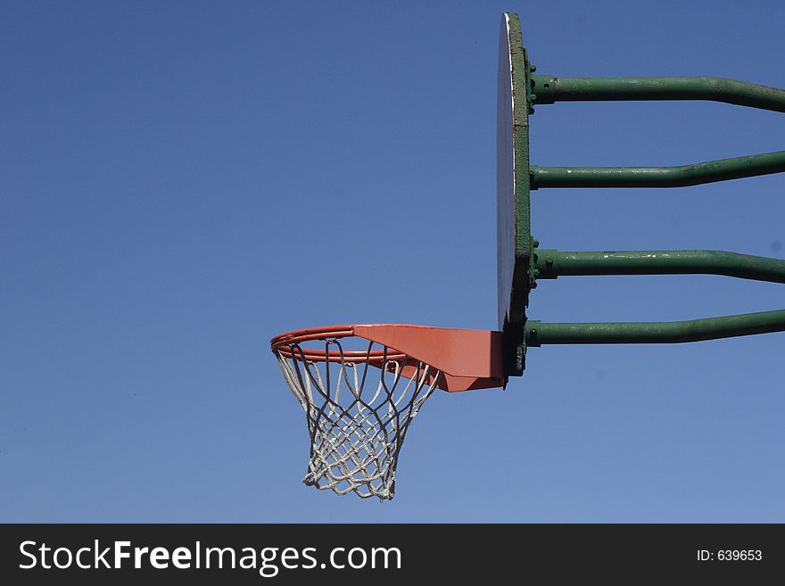 An empty outdoor basketball hoop waits for a ball to hit it. An empty outdoor basketball hoop waits for a ball to hit it