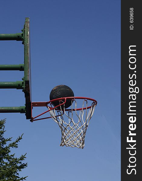 A black basketball sides the rim before sinking in. A black basketball sides the rim before sinking in