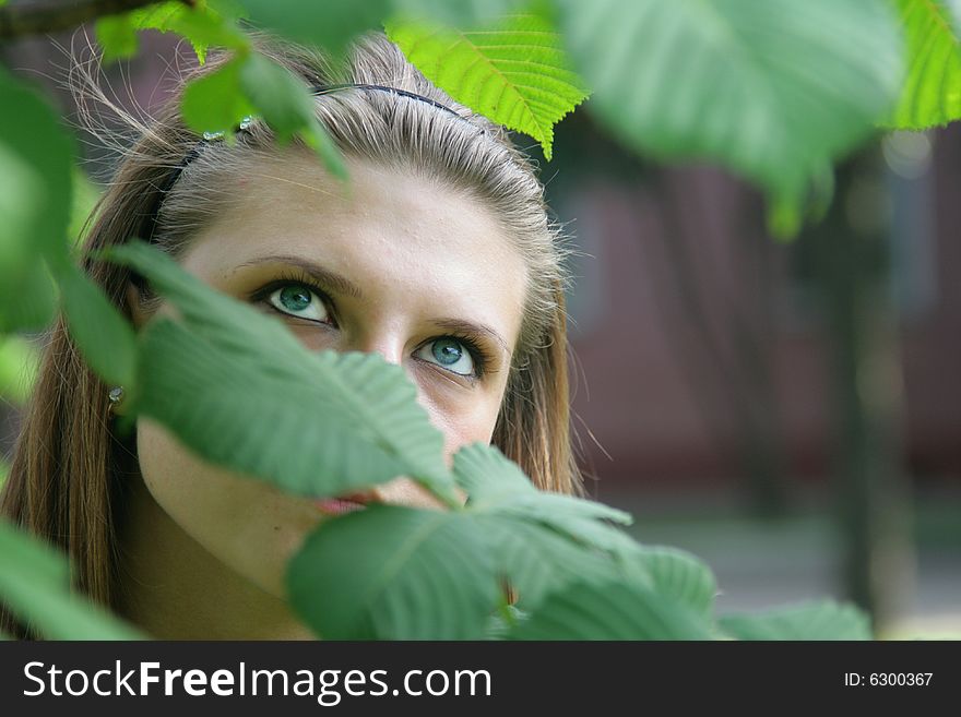 The blue-eyed girl admires green leaves