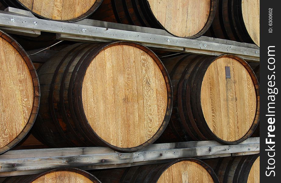 Brown wooden oak wine barrels stacked in a wooden rack