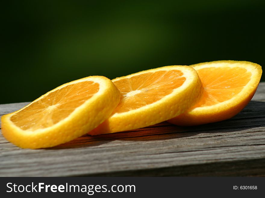 Sliced orange pieces resting on a rail in the warm sun light. Sliced orange pieces resting on a rail in the warm sun light