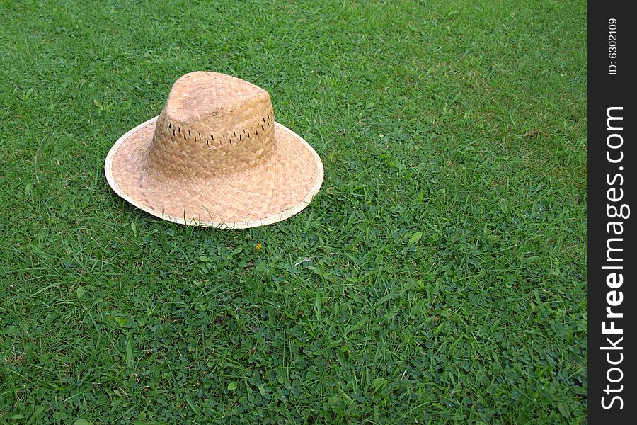 Summer photo of straw hat on a green grass lawn. Summer photo of straw hat on a green grass lawn.