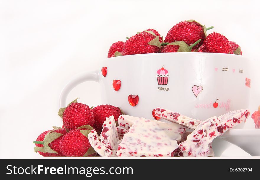 Raspberry and white chocolate candy with a decorated valentine cup on a white background. Raspberry and white chocolate candy with a decorated valentine cup on a white background