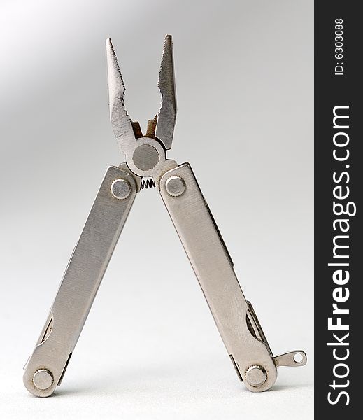 Small simple stainless pliers on a gray background