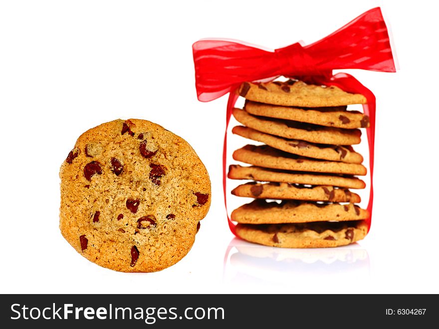 One chocolate chip cookie next to a stack of cookies wrapped with ribbon. One chocolate chip cookie next to a stack of cookies wrapped with ribbon