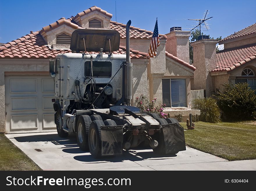 This is a picture of a big rig truck parked in front of a suburban house with an American flag. This is a picture of a big rig truck parked in front of a suburban house with an American flag.