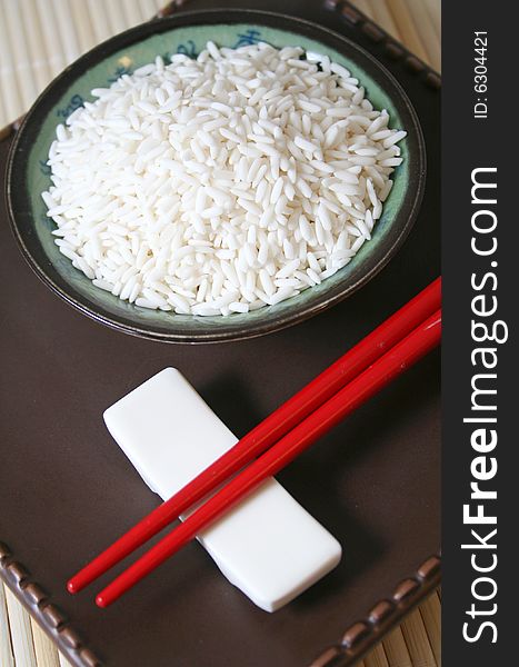 Some asian rice in a bowl with chopsticks