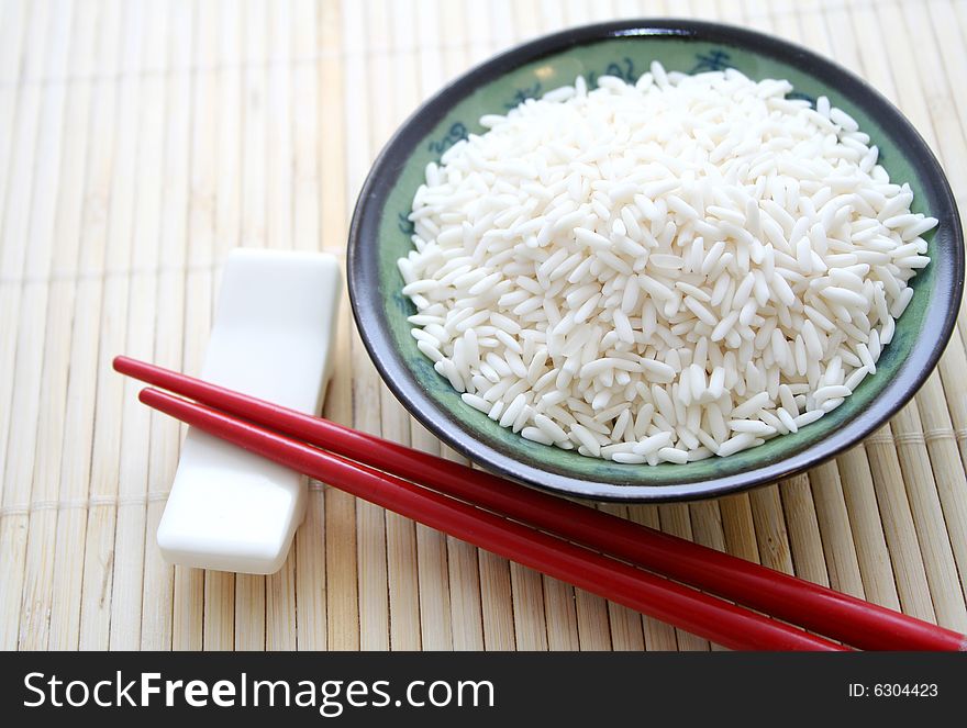 Some asian rice in a bowl with chopsticks