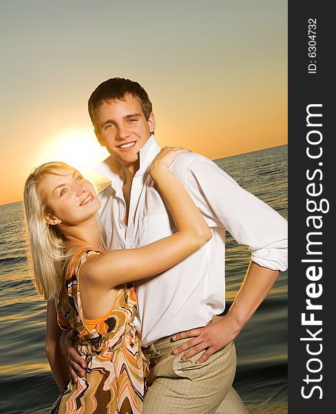 Young couple in love near the ocean at sunset