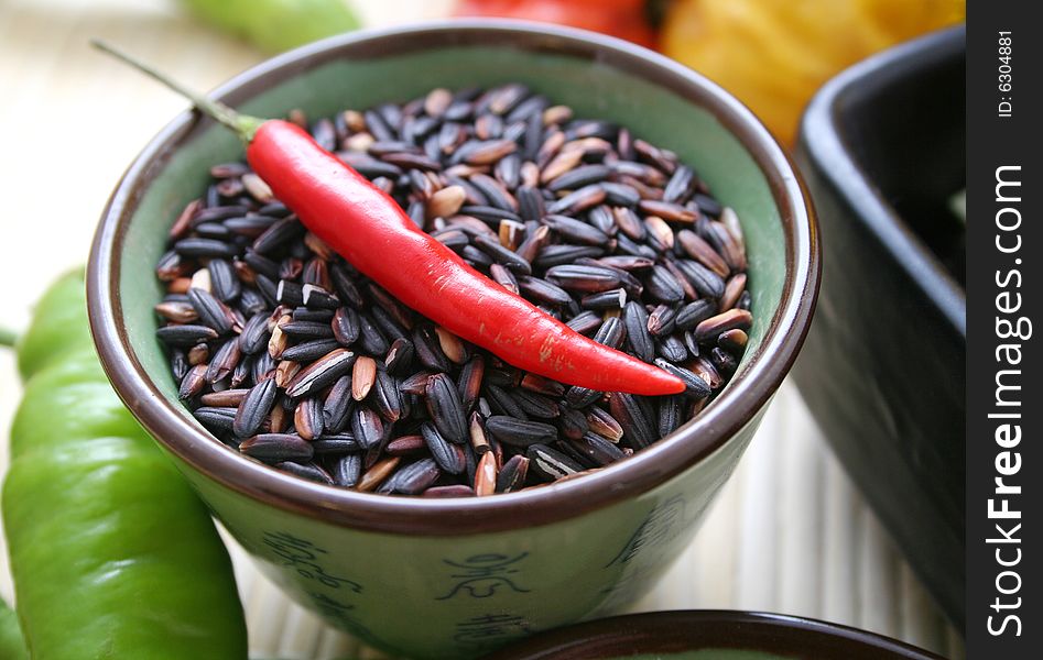 Some asian rice in a bowl with a chili