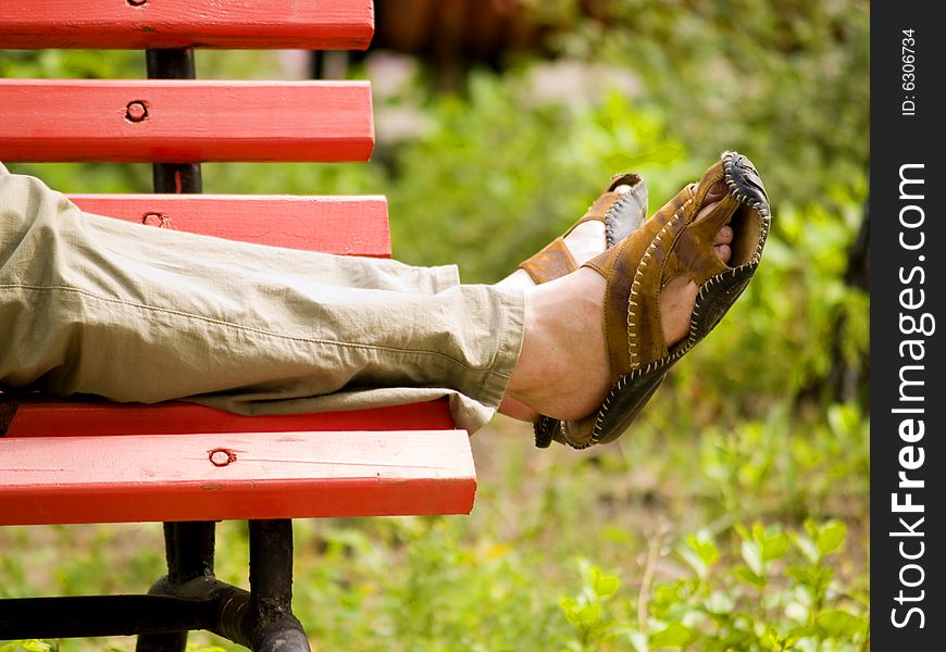 The man in sandals has a rest on a bench