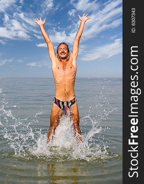 Happy man jump in sea with splashes. Happy man jump in sea with splashes