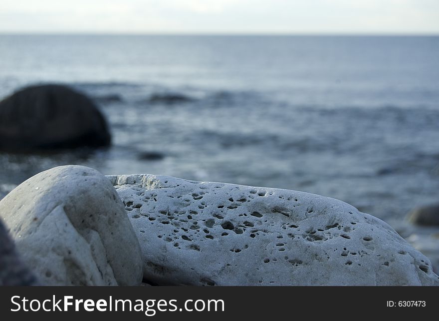 A rock on the beach with the ocean in the background. A rock on the beach with the ocean in the background.