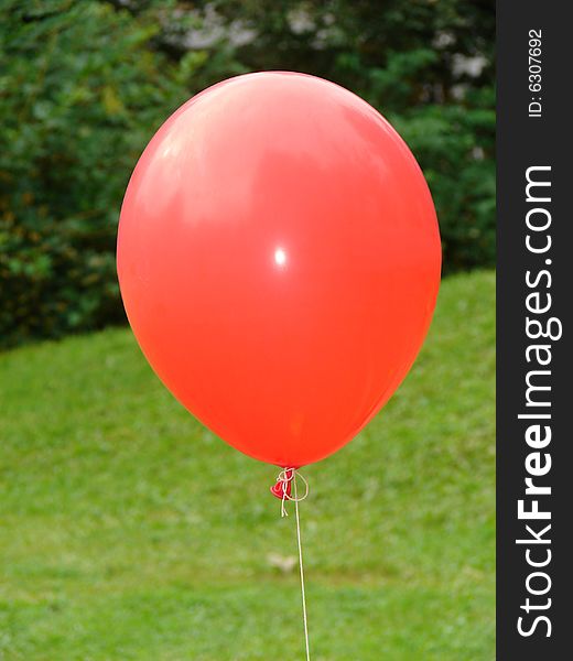 Red balloon on background a green grass