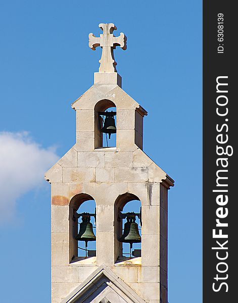 On a photo belltower  on a background of the blue sky. On a photo belltower  on a background of the blue sky.