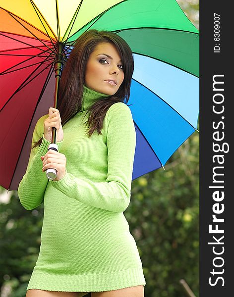 Beautiful woman with colorful umbrella relaxing in park. Beautiful woman with colorful umbrella relaxing in park